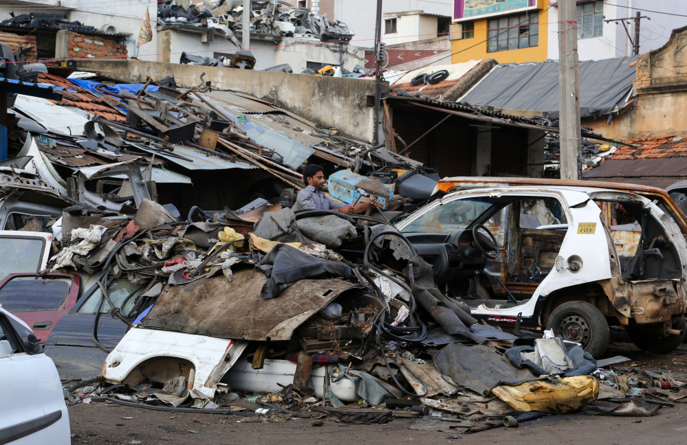A man dismantles an old car amid heaps of scrap in Bangalore, India. A World Bank report spotlights how the impact of global warming will be borne disproportionately by the world’s poor, who are woefully unprepared to weather climate shocks.