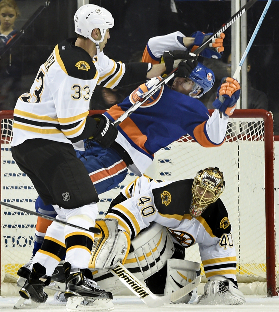 Bruins defenseman Zdeno Chara, left, shoves Islanders’ right wing Cal Clutterbuck as goalie Tuukka Rask during Boston’s 2-1 win Sunday in New York.