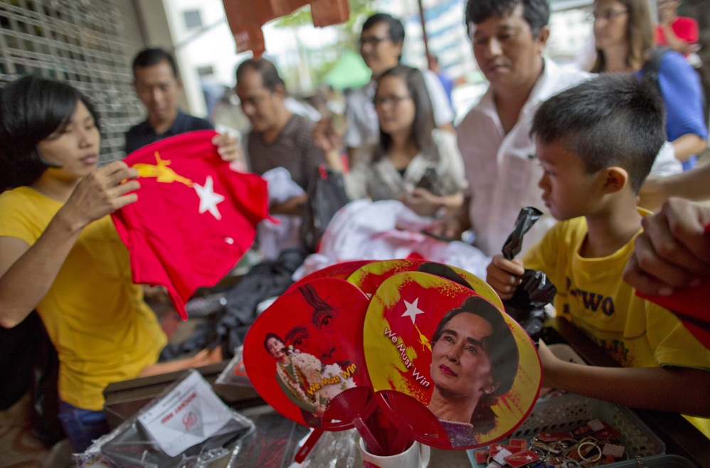 People gather to buy merchandise with pictures of opposition leader Aung San Suu Kyi at a shop run by her National League of Democracy party in Yangon, Myanmar, on Tuesday. Her party, which appears headed for a massive election victory, accused the government election panel Tuesday of intentionally delaying results, saying it may be trying “to play a trick.” (The Associated Press)