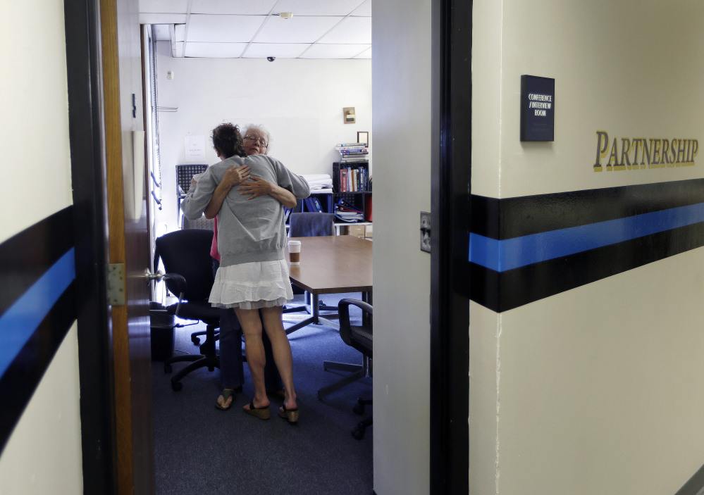 Volunteer recovery mentor Ruth Cote, facing, hugs a woman who had voluntarily come to the Gloucester (Mass.) Police Department for help kicking her heroin addiction. A similar program has launched in Scarborough, and one is planned in Augusta – but lack of access to treatment facilities and funding is a roadblock.
