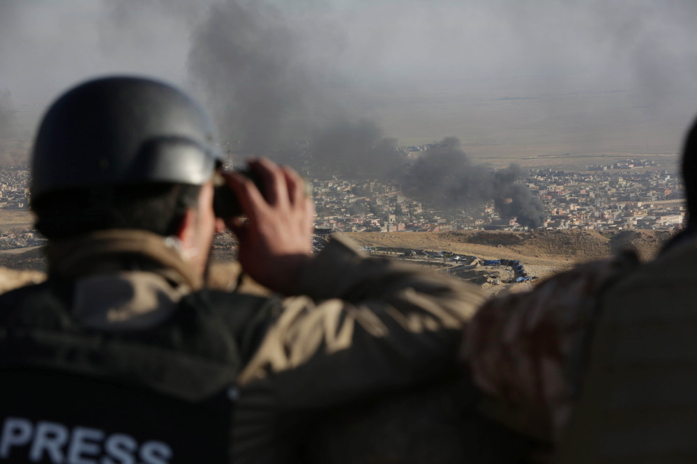 A journalist watches as smoke rises over Sinjar in northern Iraq from oil fires set by Islamic State militants as Kurdish Iraqi fighters, backed by U.S.-led airstrikes, launch a major assault on Thursday.