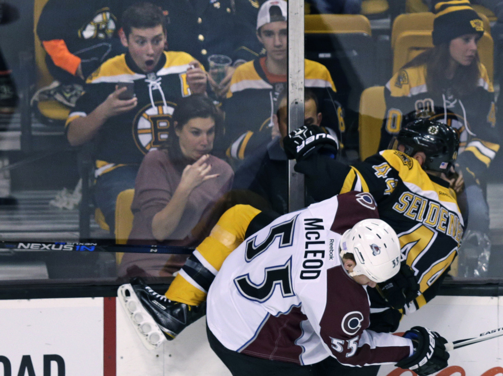 Bruins fans watch as defenseman Dennis Seidenberg, in his first game since having back surgery in the off-season, is slammed into the boards by Avalanche left wing Cody McLeod in the first period of Thursday night’s game in Boston. Seidenberg returned to the ice.