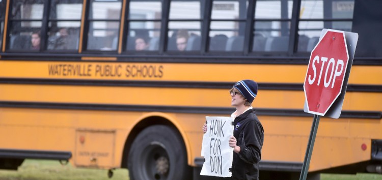 A Waterville Senior High School student stands at the exit to the high school with a sign in support of Principal Don Reiter at a support rally at the school on Friday.
