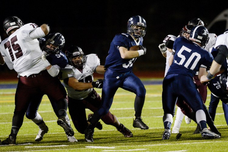Portland’s Joe Esposito runs up the middle against Windham’s defense in Friday night’s Class A North championship game.