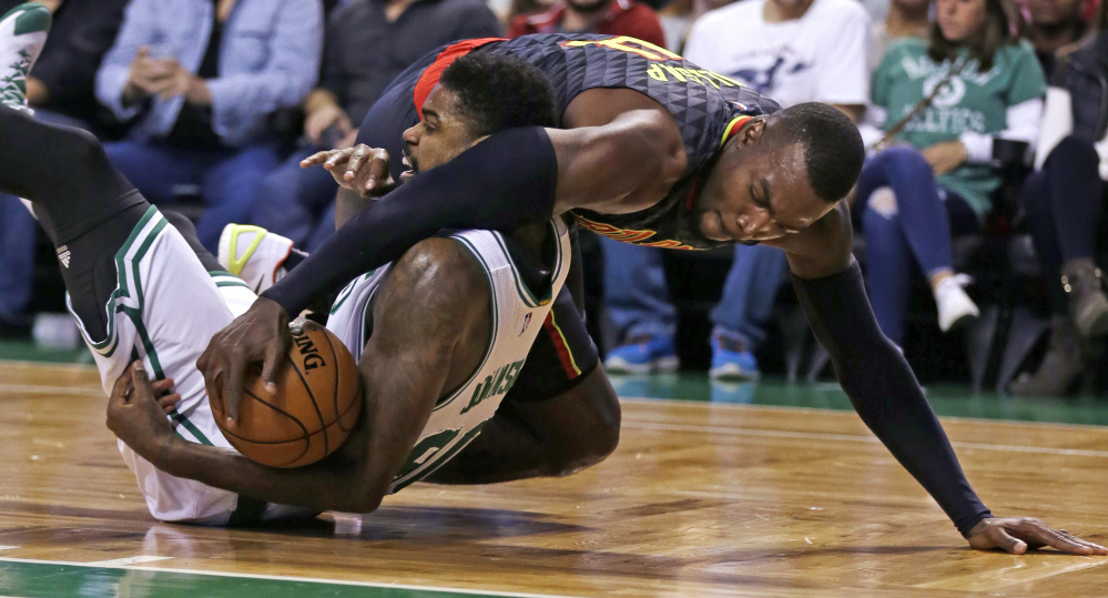 Atlanta forward Paul Millsap, top, tries to strip the ball from the grip of Celtics forward Amir Johnson as they hit the floor in the first quarter of Friday night’s game in Boston.