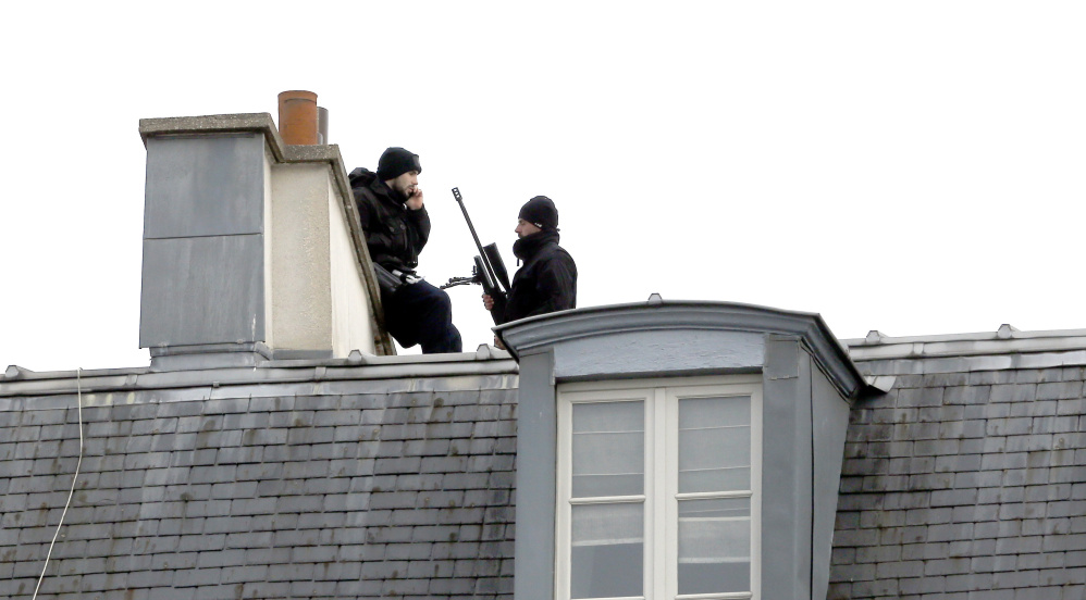 Snipers take position atop a building Saturday in front of the Elysee Palace one day after terrorist attacks rocked the French capital, killing scores of people.