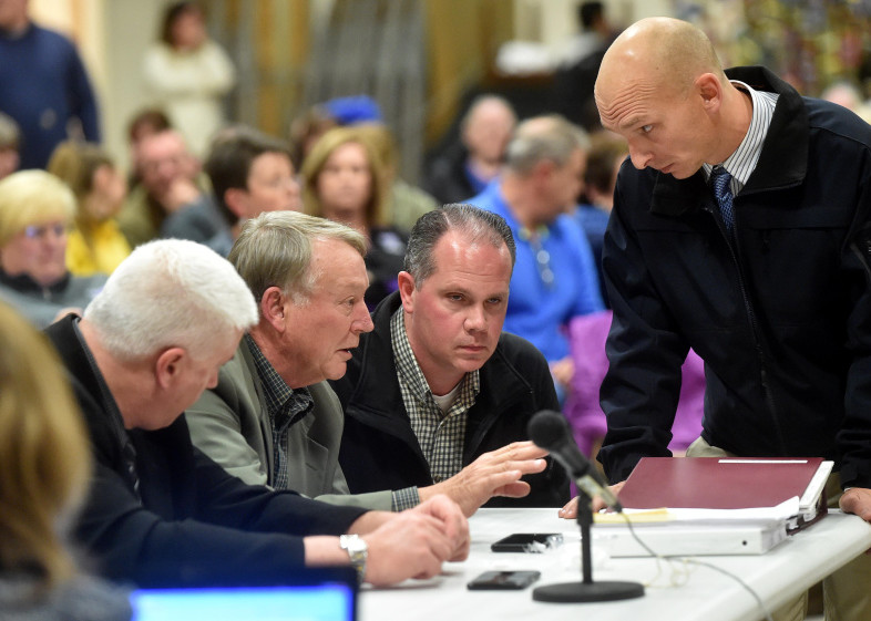 Eric Haley, left center, superintendent of schools in Waterville, confers with Waterville police detectives Dave Caron, right center, and Bill Bonney, far right, during an open hearing about allegations that Waterville Senior High School principal Don Reiter asked a student for sex, last week at George J. Mitchell School.