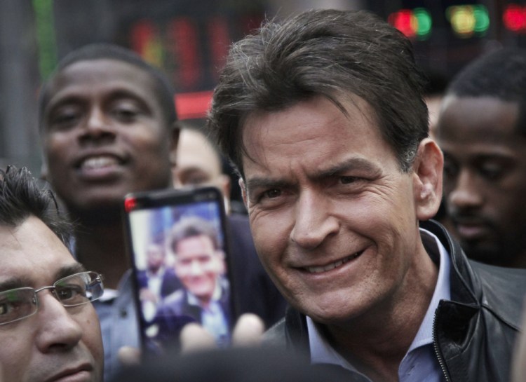In this 2013 file photo, actor Charlie Sheen is mobbed for autographs and photos as he makes his way through Times Square in New York.