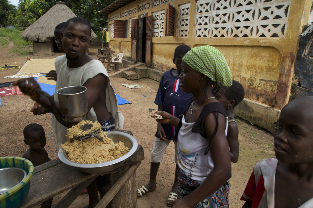 A man, left, grinds peanuts into a mash to sell to people in the village of Tanah, Guinea. West Africa’s Ebola outbreak is down to a handful of cases and they are all in Guinea where the disease first emerged nearly two years ago and where health workers battle community resistance in their bid to extinguish the disease. The Associated Press
