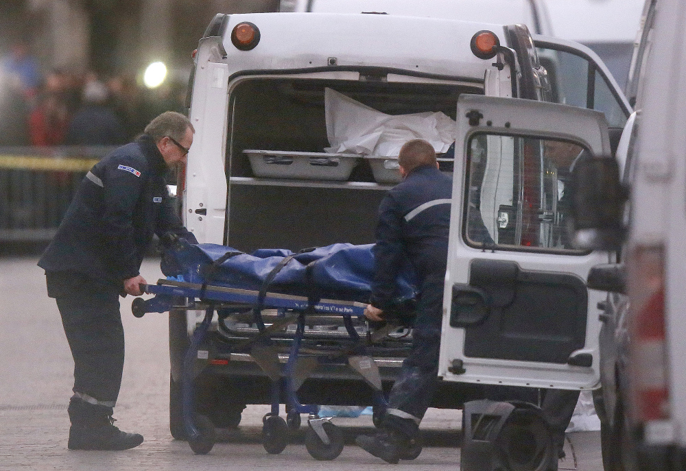 Two men carry a body into a hearse after Wednesday’s police raid in which the leader of the Paris attacks and his cousin died. A tip from outside Europe and a discarded cellphone led authorities to the apartment building in Saint-Denis.