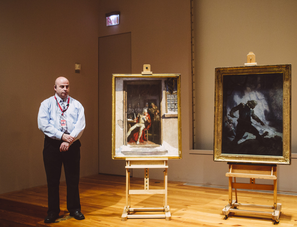 Portland Museum of Art security officer Shawn Higgins stands with two N.C. Wyeth paintings during a news conference Thursday announcing their recovery by the FBI. Wyeth is the father of Andrew Wyeth, one of the best-known American artists of the mid-20th century. The value of the two paintings is unclear.