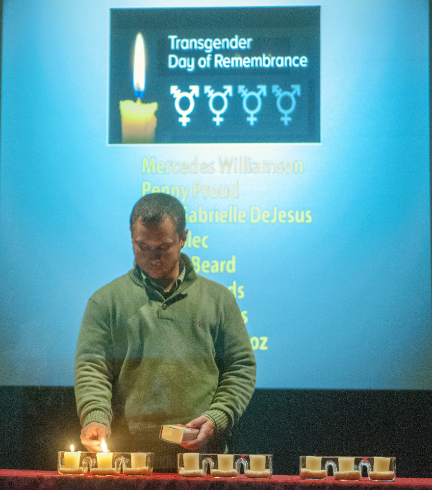 After reading a page of names of murder victims, Matthew Francis lights a candle during a transgender memorial event at the Holocaust and Human Rights Center of Maine at the University of Maine at Augusta.