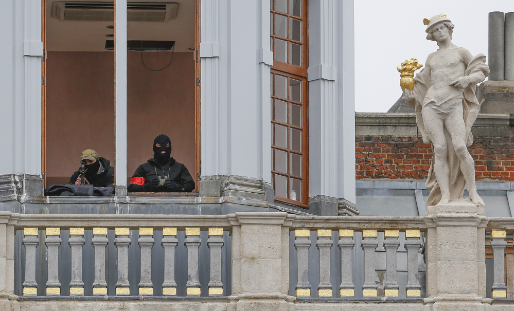 A sniper and an observer of the Belgian police special forces keep watch from the balcony of a building on Brussels Grand Place on Friday after security was tightened in Belgium following the fatal terror attacks in Paris.