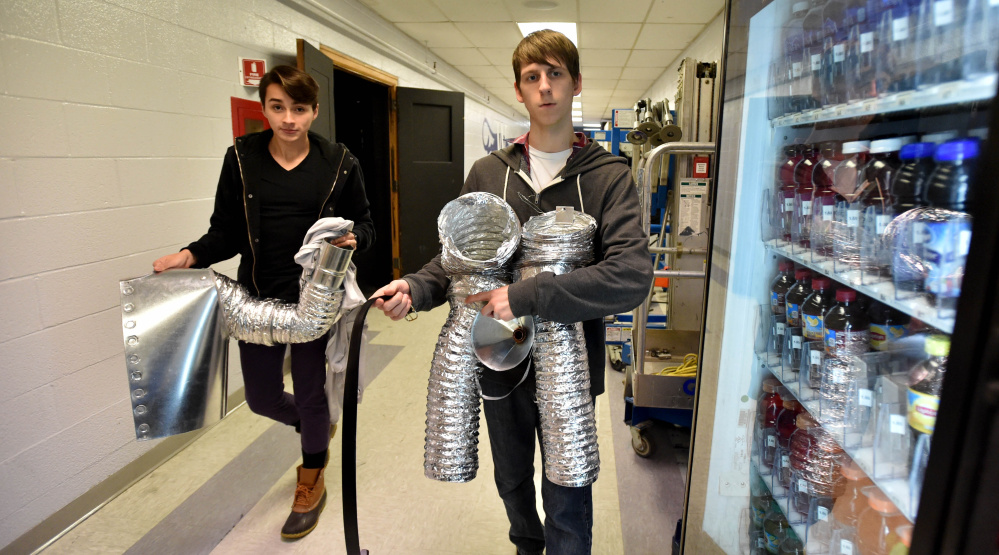 Alan Baez, left, and Austin Witham carry sections of the Tin Man costume to the dressing area at Trask Auditorium.