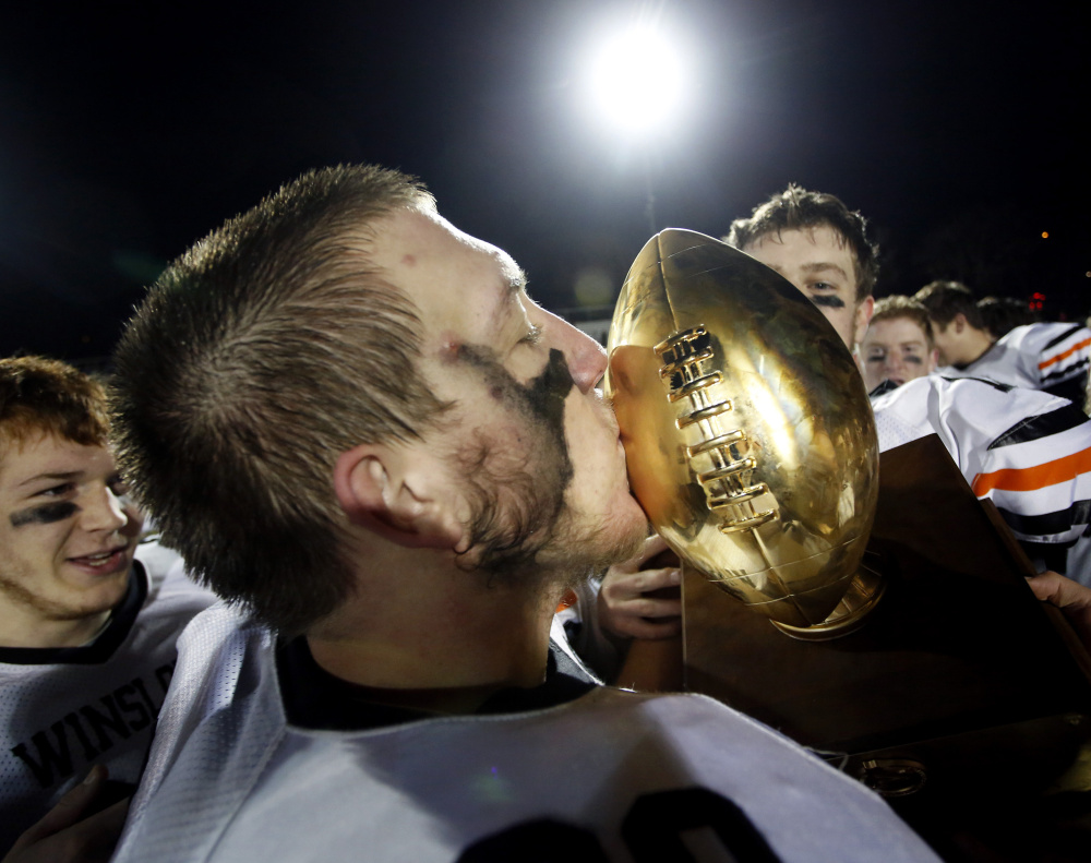 Nat Beckwith of Winslow takes his turn giving the Gold Ball a kiss after the Black Raiders beat Yarmouth, 24-10, for the Class C title.