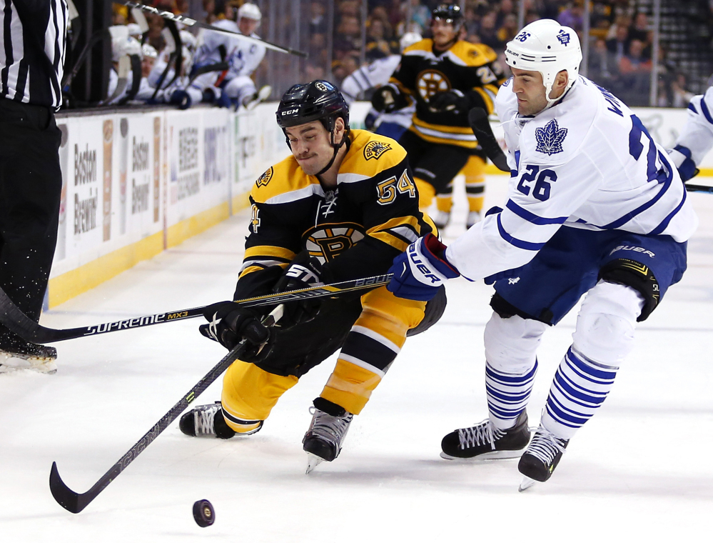 Bruins defenseman Adam McQuaid battles for the puck with Toronto’s Daniel Winnik during their game Saturday night in Boston. The Bruins won, 2-0.