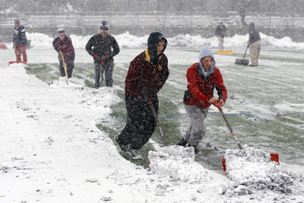 Crews at Montini High School work to remove snow from the field before the Class 6A semifinal high school football game against Prairie Ridge in Lombard, Ill., on Saturday.