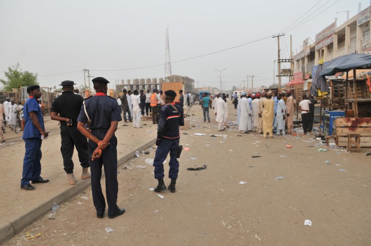 Security officers stand guard at the scene of an  explosion at a mobile phone market Wednesday in Kano, Nigeria.