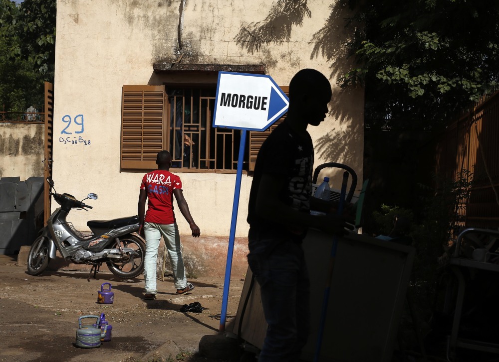 Hospital workers walk outside the morgue in Bamako, Mali where two heavily armed men shot up a hotel in the capital city last Friday, killing 19 people. State media showed photos of the dead attackers Monday as officials seek information.