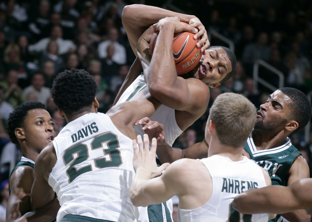 Michigan State’s Marvin Clark Jr. pulls down a rebound over Eastern Michigan’s Jordan Nobles, left, and Jodan Price, right, during the Spartans’ 89-65 win Monday at East Lansing, Michigan.