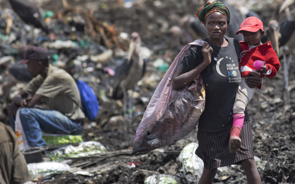 Agnes Njoki, 17, carries her daughter Shantel Akinyi, 2, as she works scavenging for plastic at the garbage dump in the Dandora slum of Nairobi, Kenya.