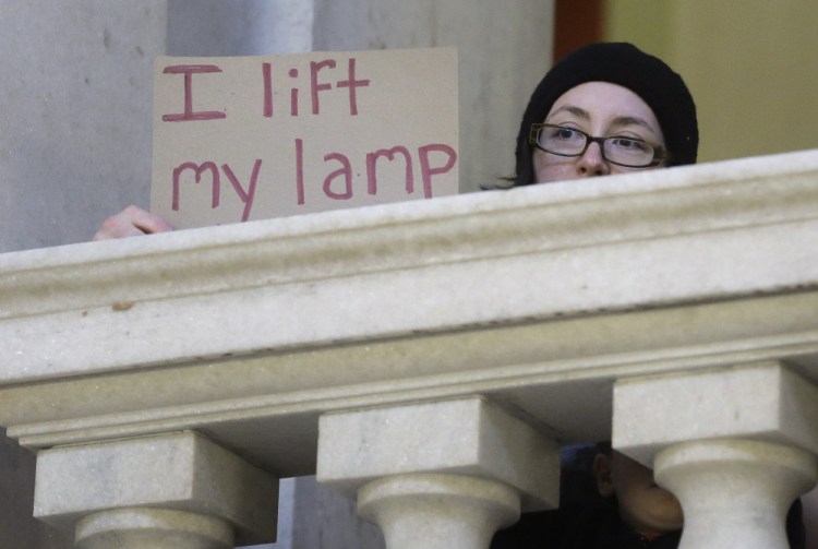 Kate Elliott displays a placard during a rally in Providence, R.I., demanding that Syrian refugees be allowed to enter Rhode Island. A reader says Americans should warmly welcome the refugees.