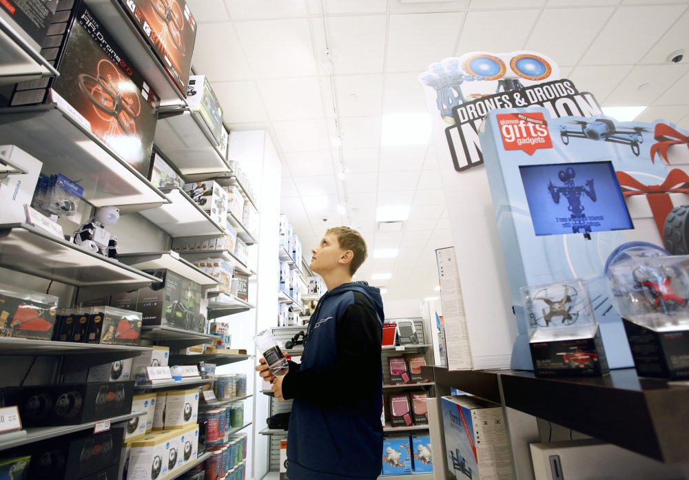 Jett Wing of Standish surveys a wall of drones in the Maine Mall. Sales are fast increasing over last year, and some makers have cut prices before new FAA rules take effect. Derek Davis/Staff Photographer