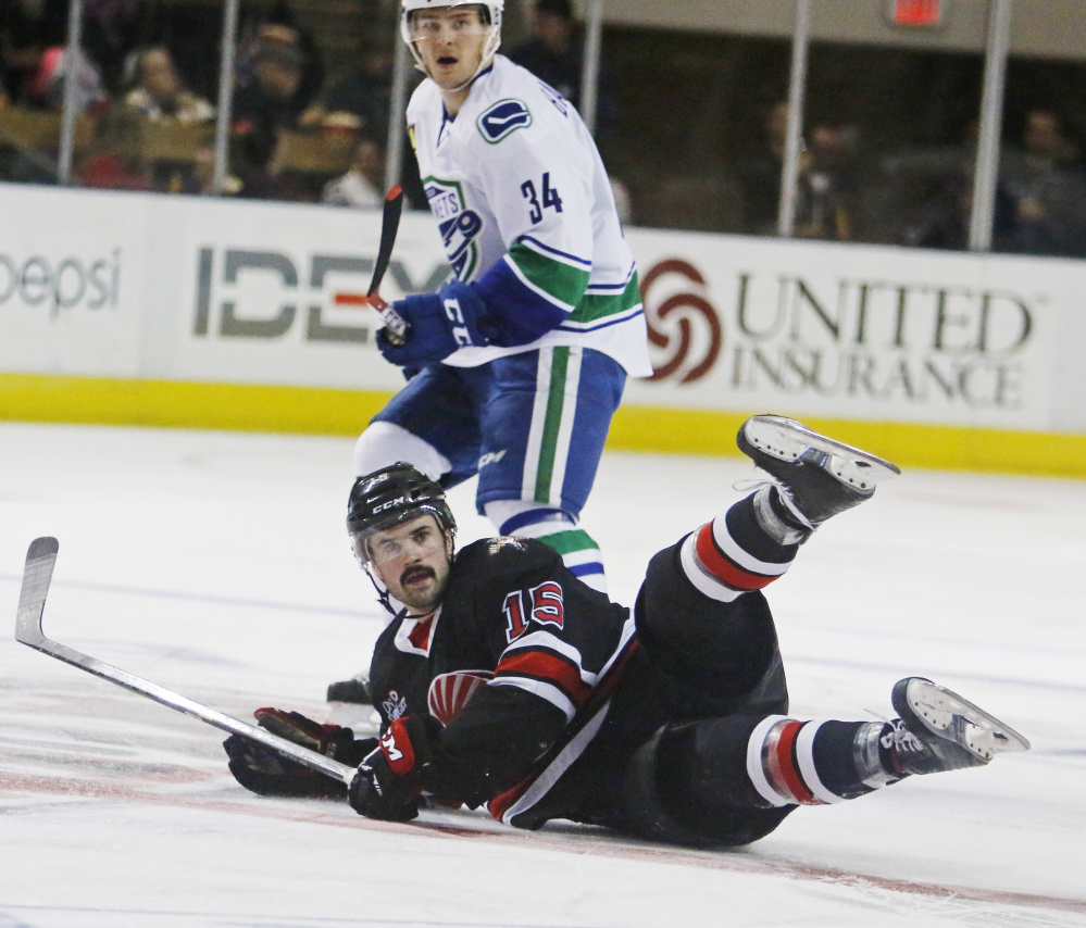 John McFarland of the Portland Pirates hits the ice Friday night in front of Carter Bancks, who scored two goals for the Utica Comets in a 4-1 vicotry at the Cross Insurance Arena. The teams meet again Saturday night.