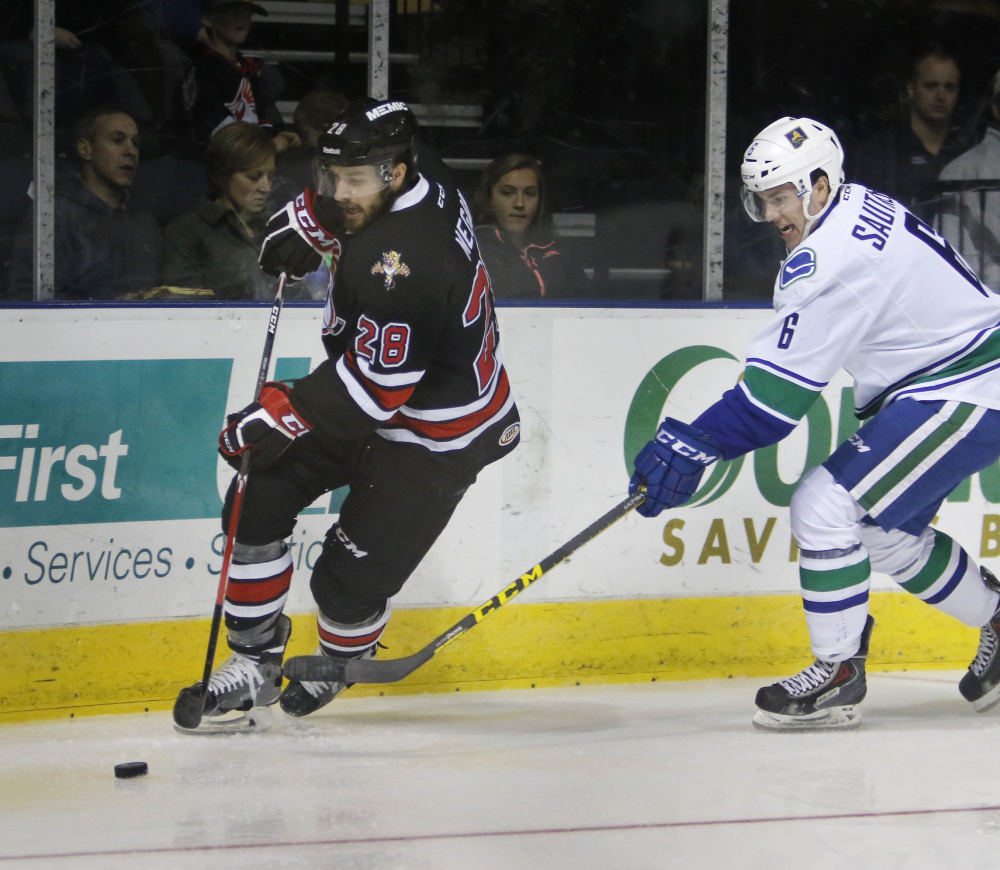 Wade Megan of the Portland Pirates moves the puck along the boards while being pressured by Ashton Sautner of the Utica Comets during the second period.