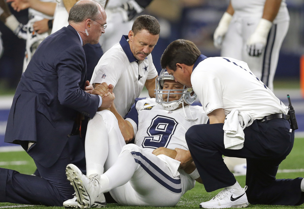 Cowboys quarterback Tony Romo is helped off the field Thursday. Romo reinjured the collarbone that kept him out for seven games earlier this season.