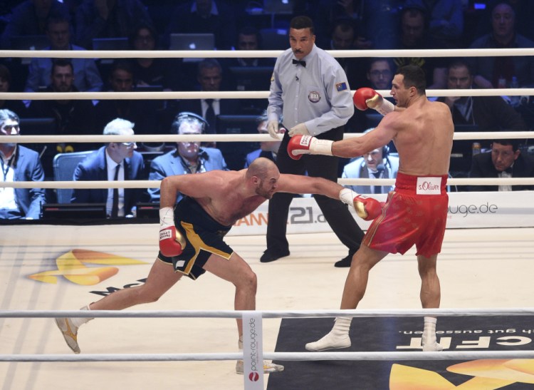 Ukraine’s Wladimir Klitschko, right, and Britain’s Tyson Fury exchange blows as referee Tony Weeks looks on in a world heavyweight title fight for Klitschko’s WBA, IBF, WBO and  IBO belts in the Esprit Arena in Duesseldorf, Germany, Saturday. Fury won a unanimous decision. The Associated Press