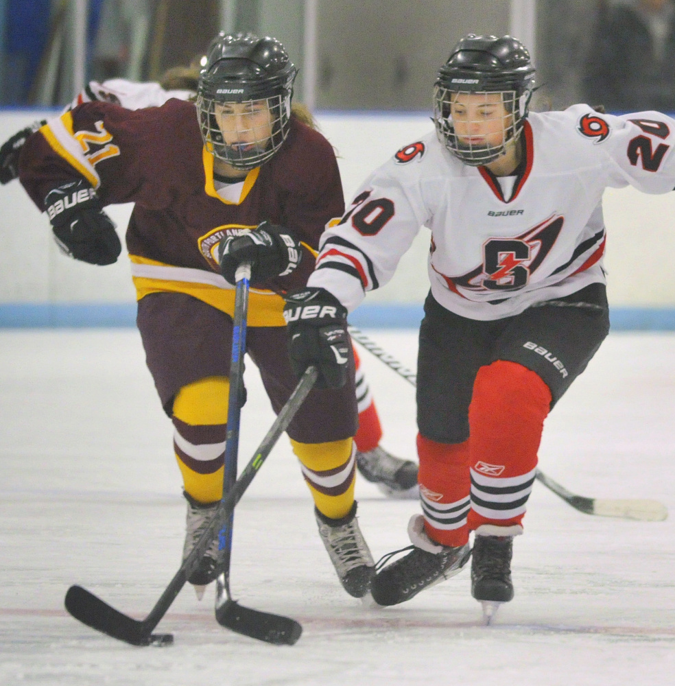 Annie Citrine of Cape Elizabeth, left, and Logan Bruns of Scarborough compete for the puck Saturday during their girls’ hockey game in Saco. Scarborough remained undefeated – two wins and a tie – with a 2-0 victory.