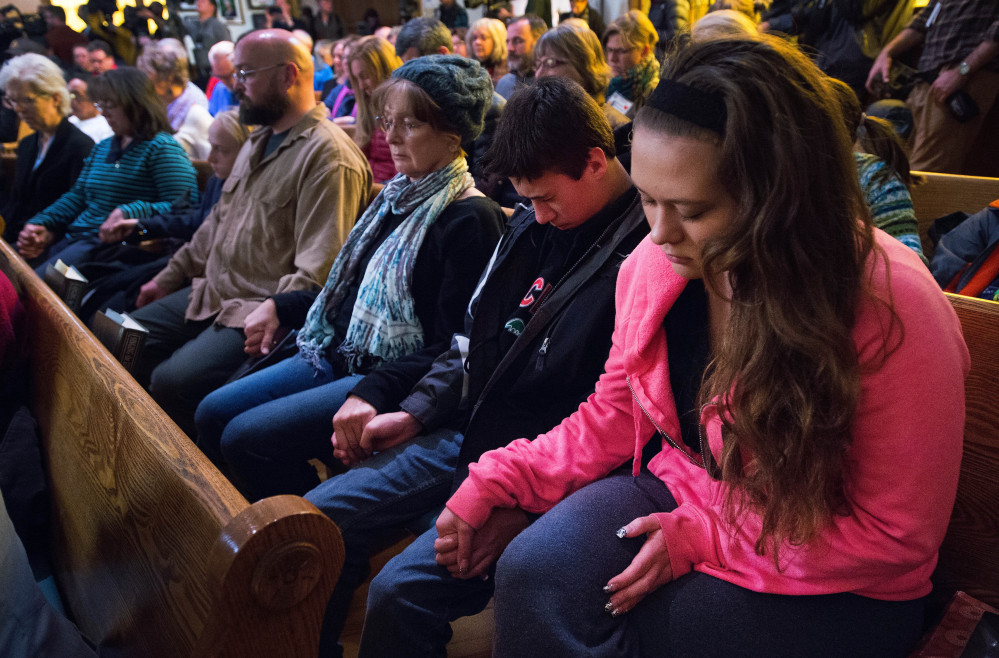 Mourners hold hands Saturday during a vigil for victims of Friday’s deadly shooting in Colorado Springs, Colo. Korina Ciuba, right, her brother Gage Ciuba and their grandmother Jean Harmon of Colorado Springs hold hands Saturday with fellow mourners during a vigil held at the All Souls Unitarian Universalist Church for those killed in Friday’s deadly shooting at a Planned Parenthood clinic in downtown Colorado Springs, Colo.