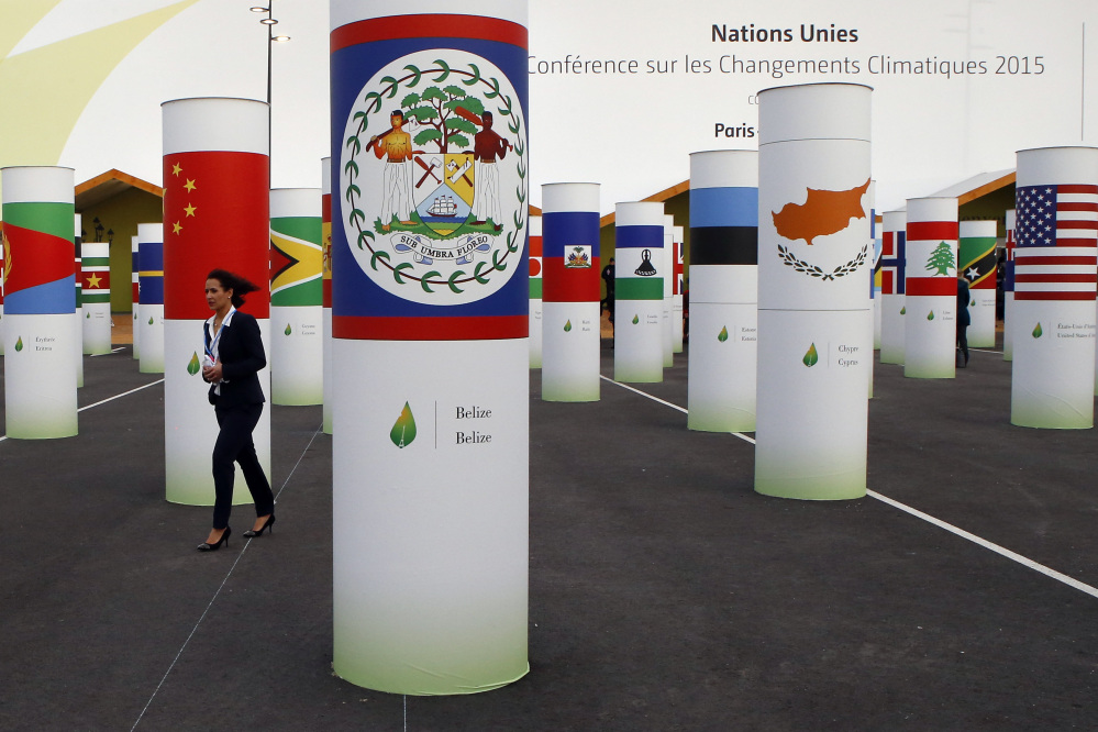 A participant walks in front of China’s flag amid more than 150 countries’ pillars decorating the entrance of the COP21, United Nations Climate Change Conference, in Le Bourget, outside Paris, on Monday.