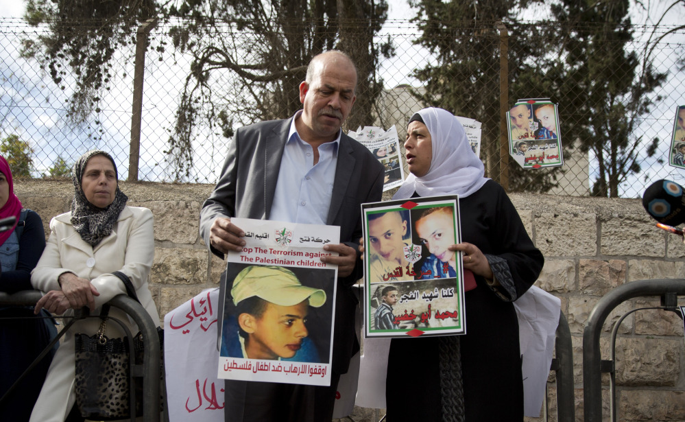 Suha and Hussein Abu Khdeir, center, parents of Mohammed Abu Khdeir, hold posters with his portrait after the reading of the verdict in his killing Monday at Jerusalem District Court. The court convicted two Israeli youths in the grisly murder of Abu Khdeir.