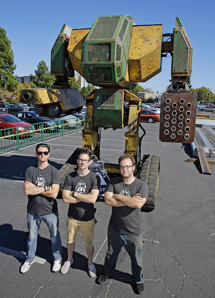 MegaBots founders from left, Brinkley Warren, Matt Oehrlein and Gui Cavalcanti stand below their 15-foot tall, piloted Mk.II robot at the Pioneer Summit in Redwood City, Calif., recently. The Associated Press