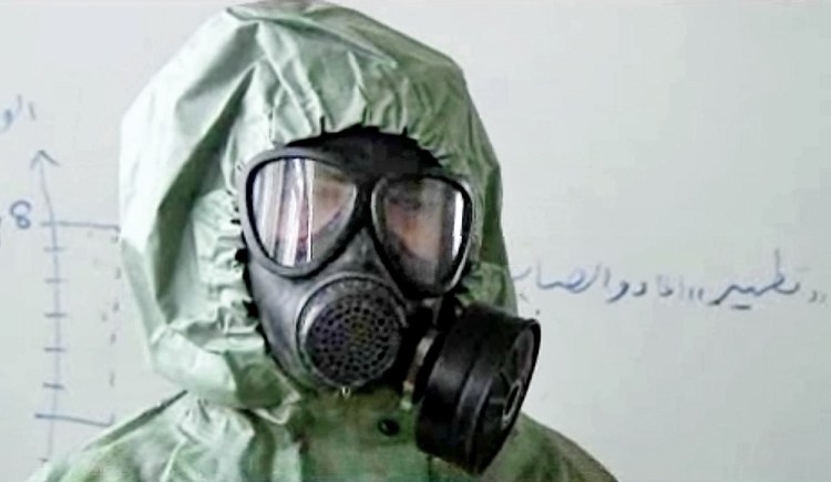 FILE - This image made from a September 2013 AP video shows a student wearing a gas mask and protective suit during a practice session on reacting  to a chemical weapons attack, in Aleppo, Syria. The Islamic State has set up a branch dedicated to chemical weapons research and experiments with the help of scientists from Iraq, Syria and elsewhere in the region, according to Iraqi and U.S. intelligence officials. 
