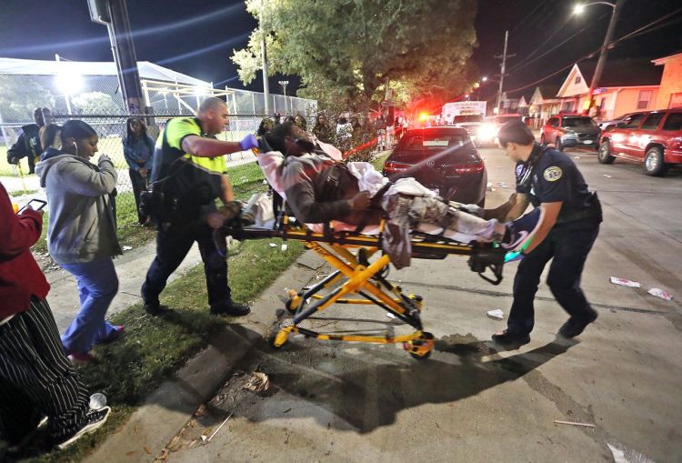 Emergency personnel remove a man from the scene of a shooting in New Orleans' 9th Ward on Sunday. Michael DeMocker/NOLA.com The Times-Picayune via AP