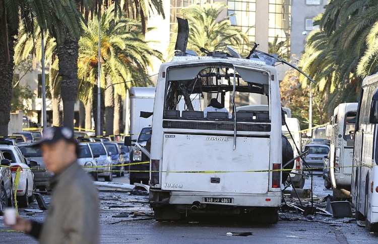 A man walks past the bus that exploded Tuesday in Tunis, Tunisia's president declared a 30-day state of emergency across the country and imposed an overnight curfew for the capital Tuesday after an explosion struck a bus carrying members of the presidential guard. The Associated Press