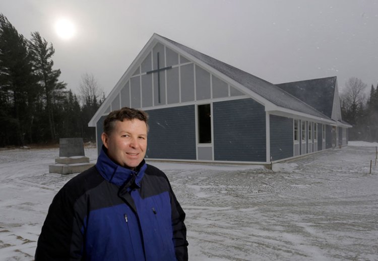 The Rev. Kevin Martin outside the new Catholic church in his northern Maine parish. The church will open its doors to his congregation 10 days before Christmas. Gabe Souza / Staff Photographer