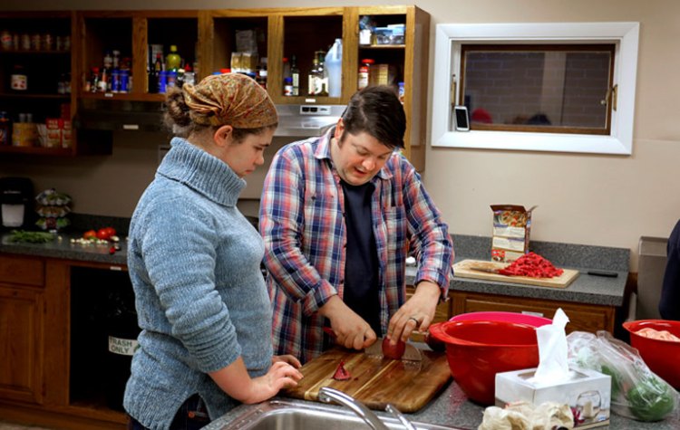 James Tranchemontagne, owner of the Frog & Turtle restaurant in Westbrook, shows Brittany Bean, 17, of Windham, how to slice onions while preparing a meal for as many as 40 kids at My Place Teen Center earlier this month. “I can’t image not being part of it,” Tranchemontagne says of the teen center. Gabe Souza/ Staff Photographer