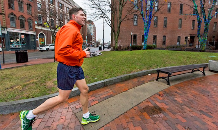 John Marshall, a visitor from Salem, New Hampshire, jogs in his shorts Thursday past the holiday lights in Tommy's Park on Exchange Street. Ben McCanna/Staff Photographer