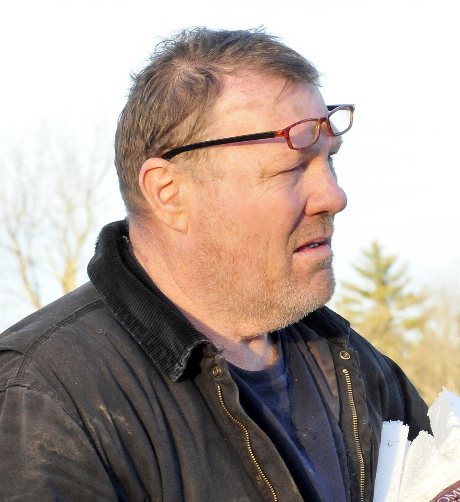 Bob Somes watches as police investigate a fatal two-car accident near his home on Route 27 in Sidney on Sunday. Somes was at the scene where one vehicle flipped over in a ravine and people removed an injured boy before the car erupted in flames with the woman driver inside, according to Somes. “The car exploded 20 seconds after the boy was removed,” Somes said. 