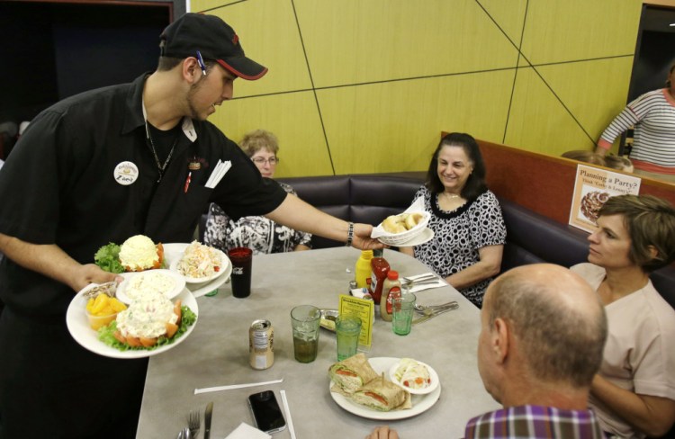 In this Friday, June 6, 2014, file photo, Zack Adams delivers food to customers at Corky & Lenny’s Restaurant & Deli in Woodmere Village, Ohio.