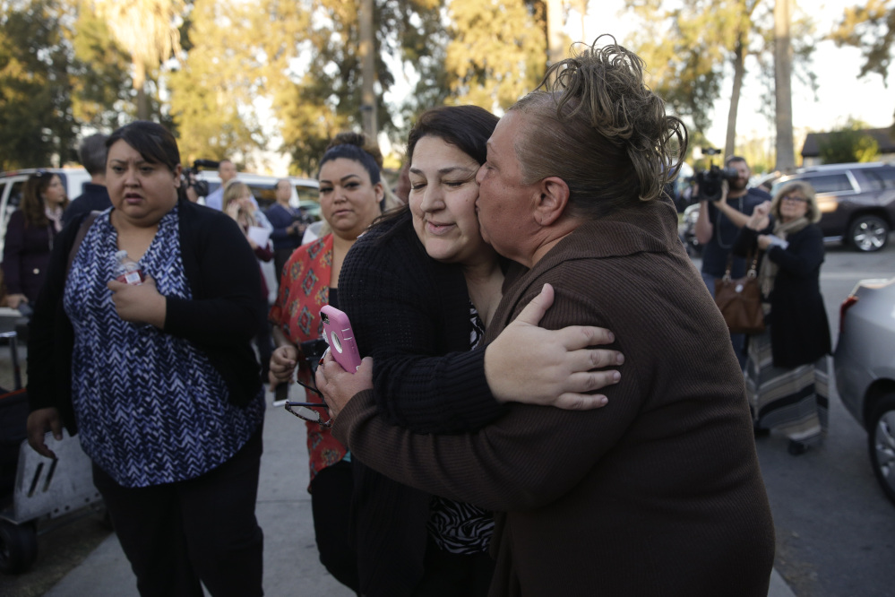 A woman who declined to give her name kisses her sister, center, who survived Wednesday’s shooting rampage in San Bernardino, Calif. More than 600 people work at the Inland Regional Center.