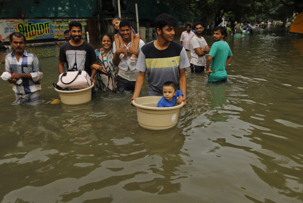 The Associated Press People with their children wade through floodwaters Thursday in Chennai, India.
