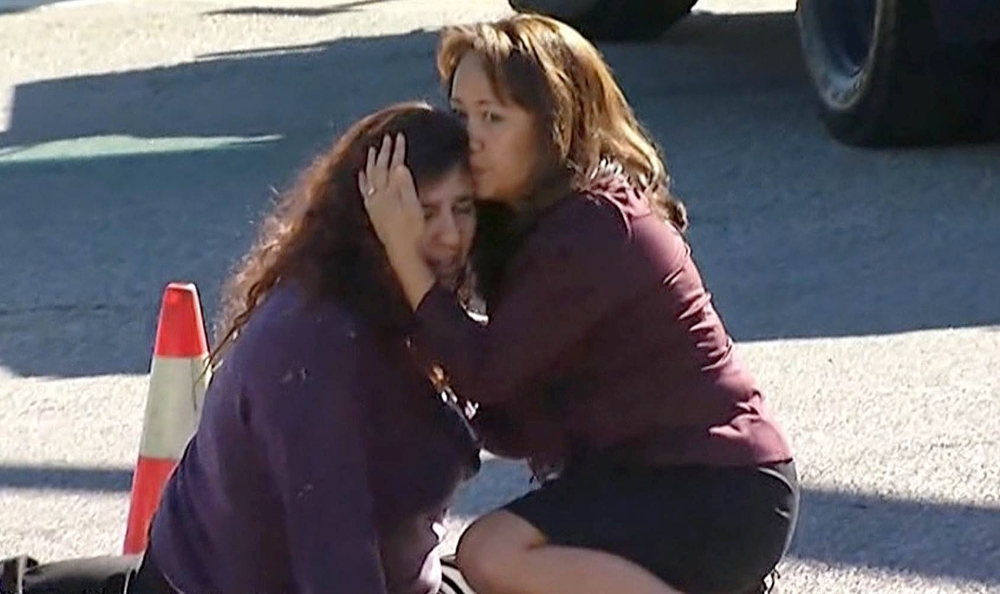 Two women comfort each other near the scene of a shooting outside a social services center in San Bernardino, Calif., where two gunmen opened fire, killing 14 people Wednesday. Authorities are still trying to determine a motive.