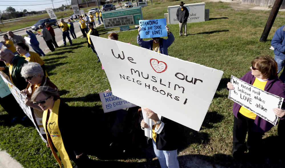Paula Criswell, center, holds a sign as she joins others in a rally to show support for Muslim members of the community near the Clear Lake Islamic Center in Webster, Texas, on Friday. Members of several Unitarian Universalist churches and the Unitarian Voices for Justice group showed their support as attendees made their way to the center for Friday prayers. The Associated Press