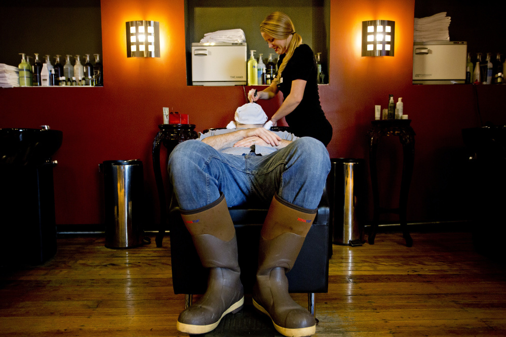 Allen Baldwin of Portland receives a hot towel treatment from Alicia Newcomb before his haircut at Mensroom Salon & Lounge in Portland. Owner June Juliano started the salon because she saw how uncomfortable men were at a woman’s salon. Gabe Souza/Staff Photographer