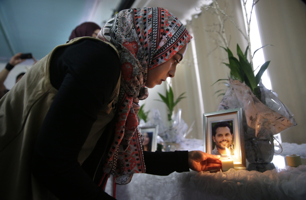 Khadija Zadeh lights candles next to the framed photos of 14 victims killed in Wednesday’s shooting rampage before the start of Sunday’s memorial service at the Islamic Community Center of Redlands in Loma Linda, Calif.